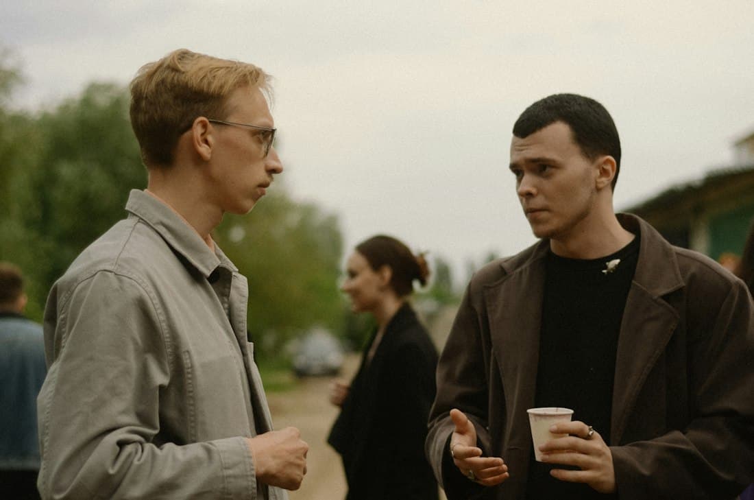 Two young men talking outdoors with coffee